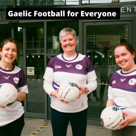 Three women standing outside the Trinity Sports Centre in Trinity College Dublin. They are all holding Gaelic footballs and wearing Purple and White stripped tops with GAA logo and Trinity Ability co_op logo. 